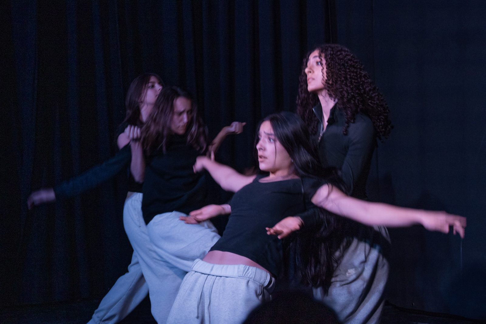 Dancers performing under dramatic purple stage lighting