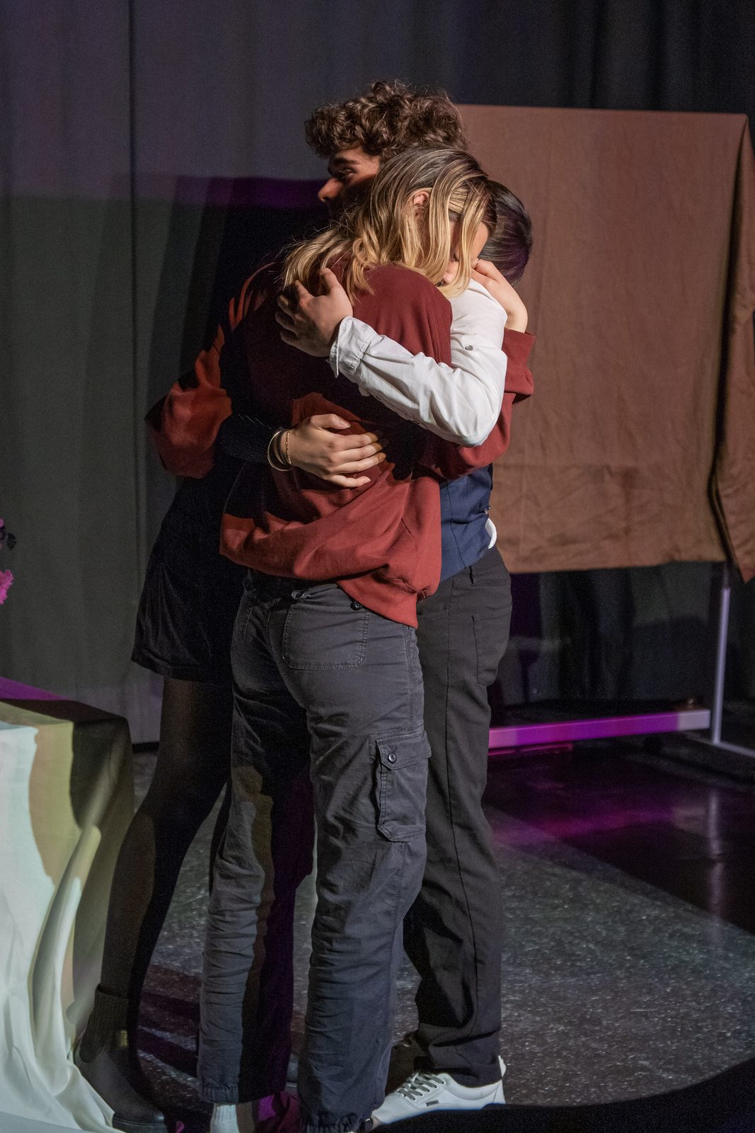 Two performers embracing in an emotional moment on stage