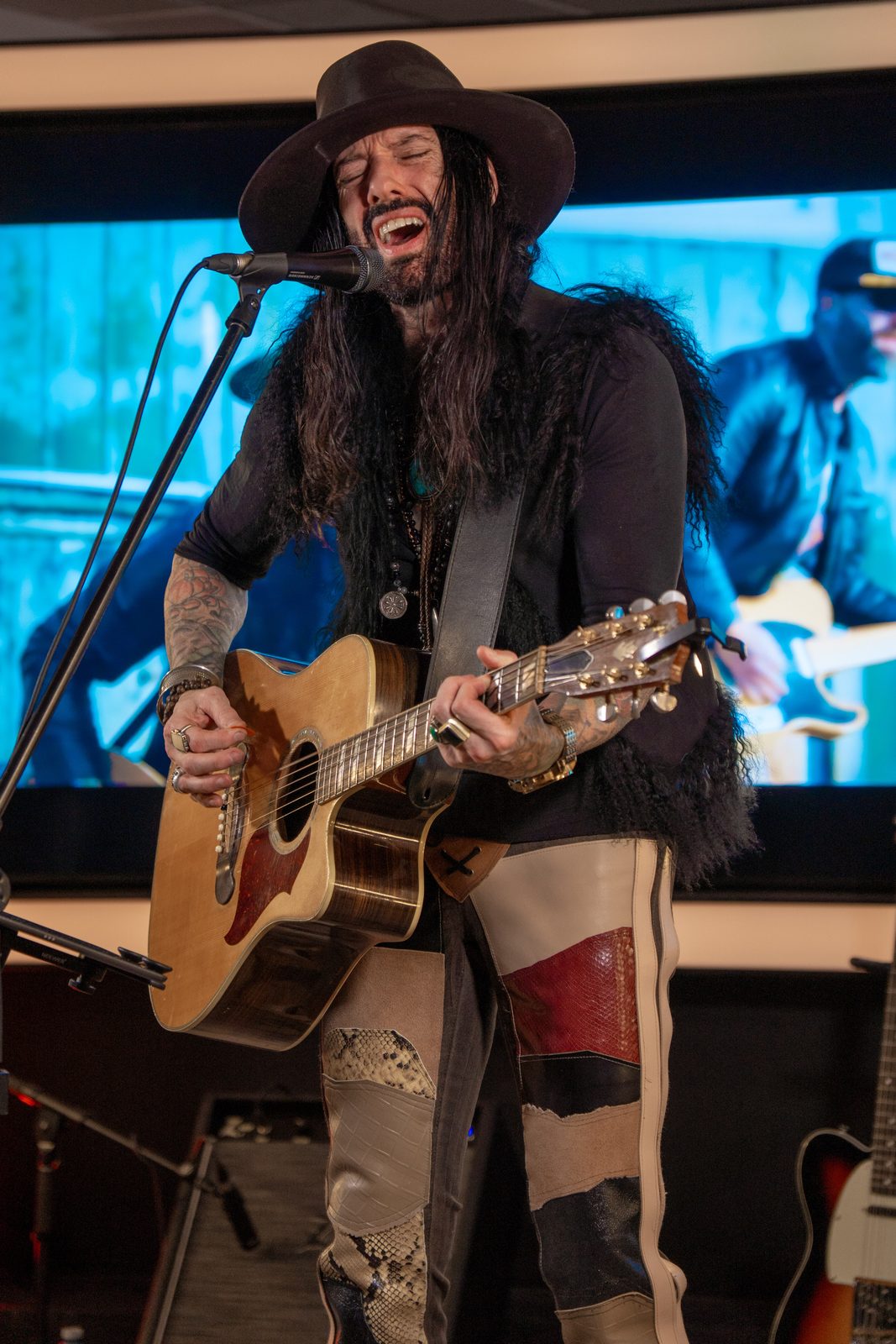 Singer-songwriter performing with an acoustic guitar under stage lights