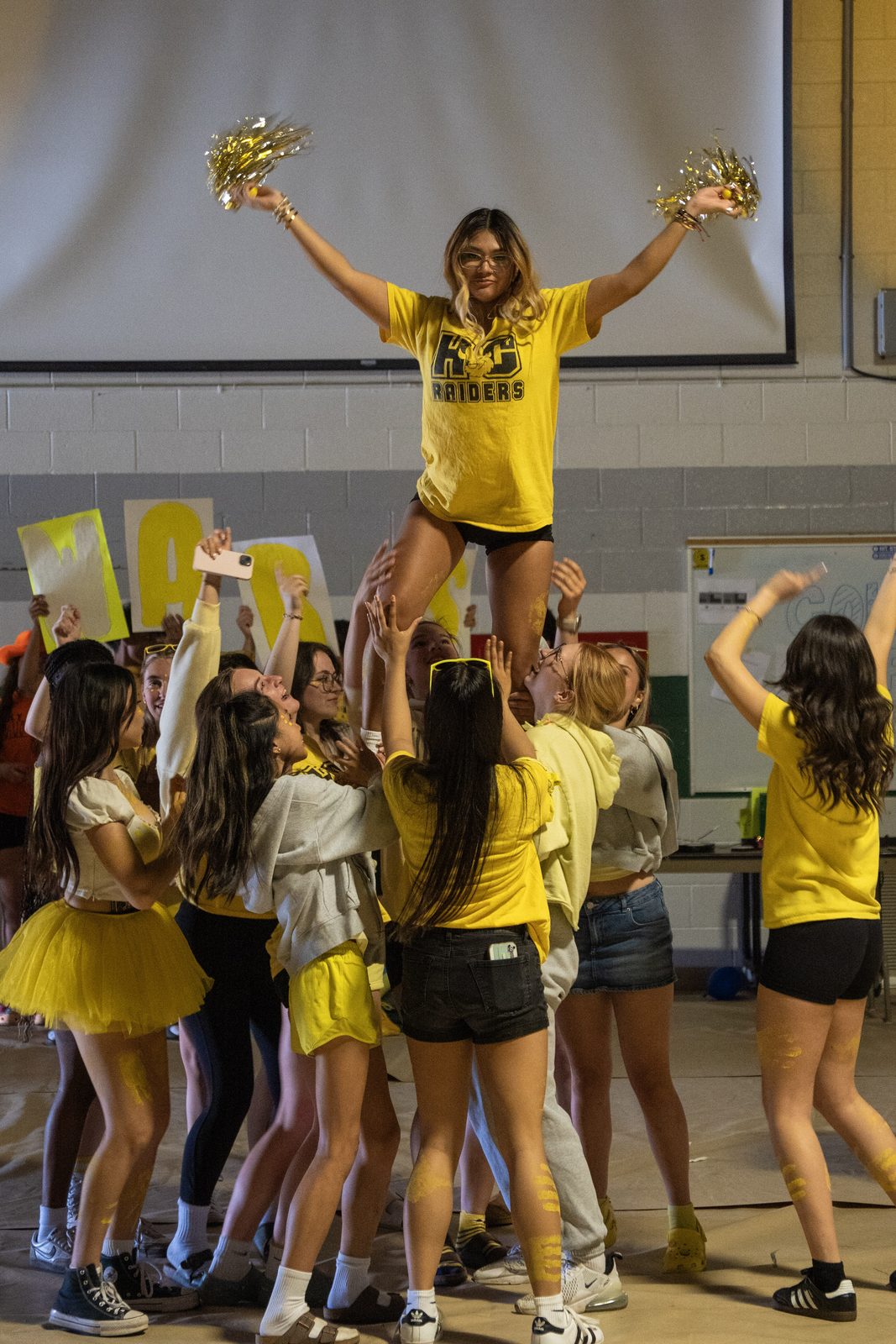 Cheer team performing with pom-poms in the gym